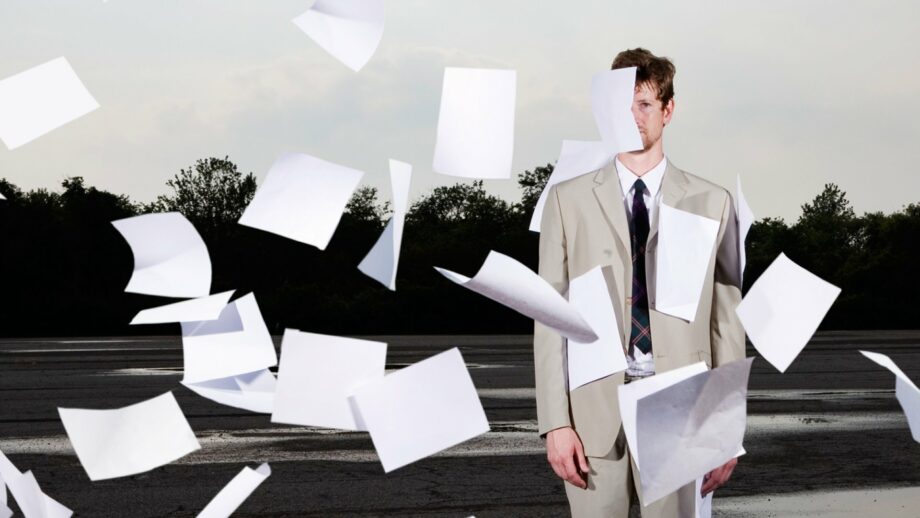 man overwhelmed by papers floating around