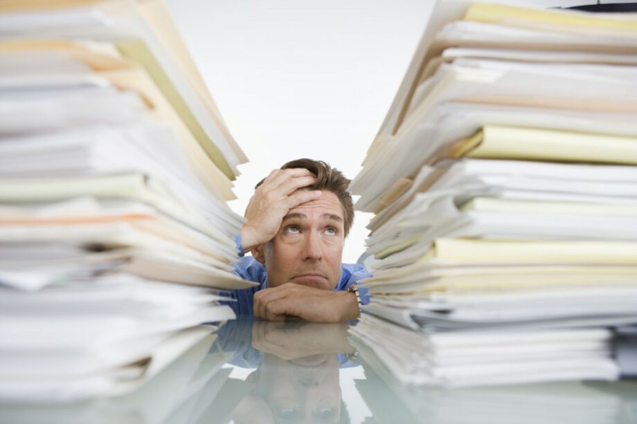 man stressed with high piles of papers